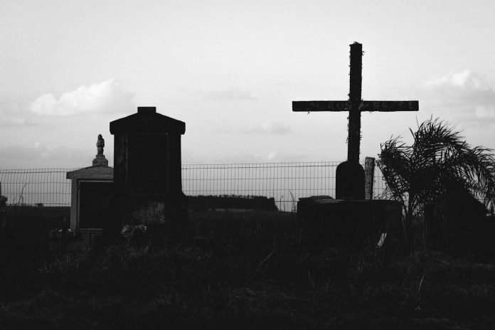 Photo by Cassiano K. Wehr a black and white photo of a cemetery with a cross